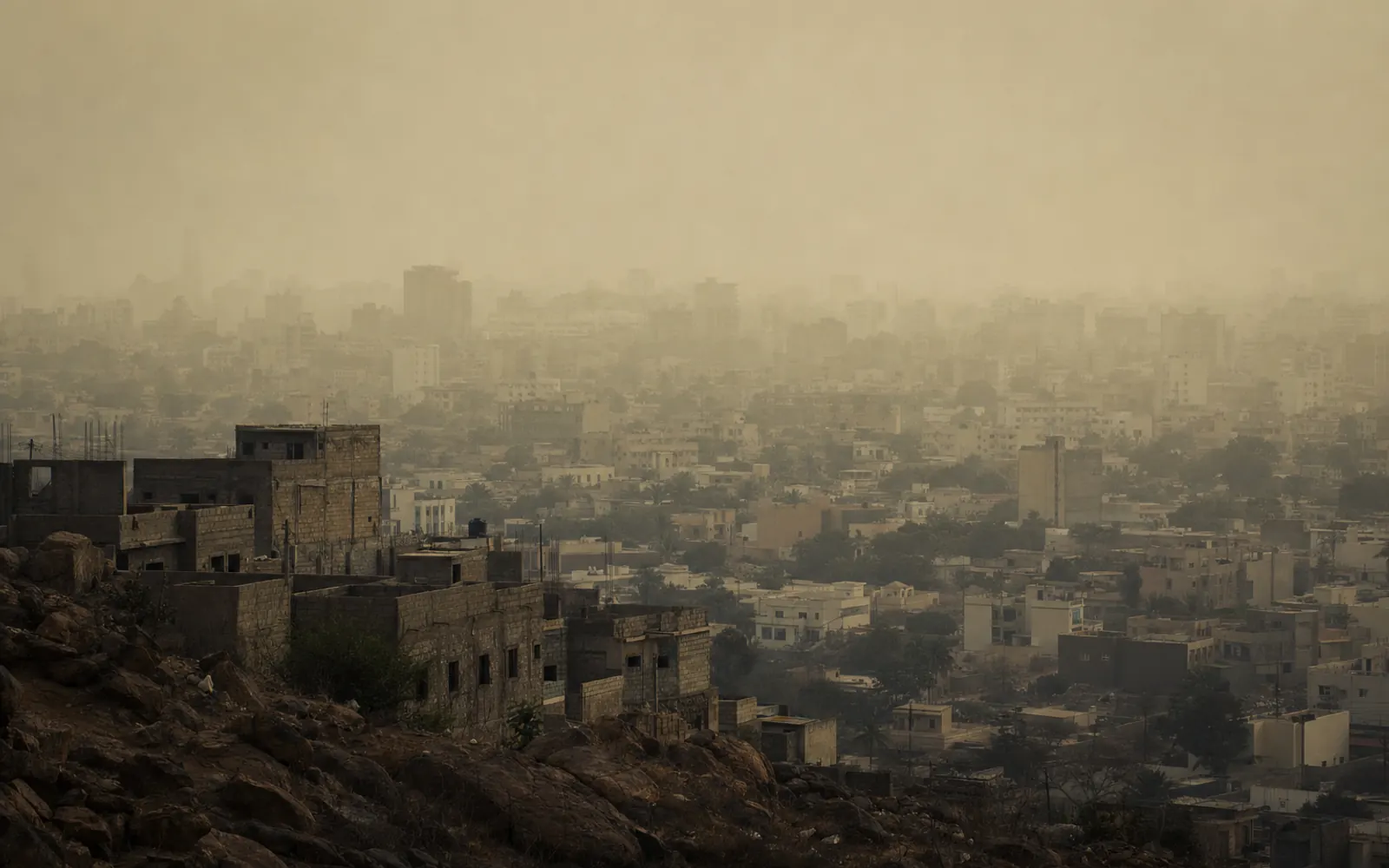 Dakar sous la brume de poussière de l'harmattan : des plans de bâtiments s'effacent successivement dans un voile jaune-gris, l'horizon a disparu.